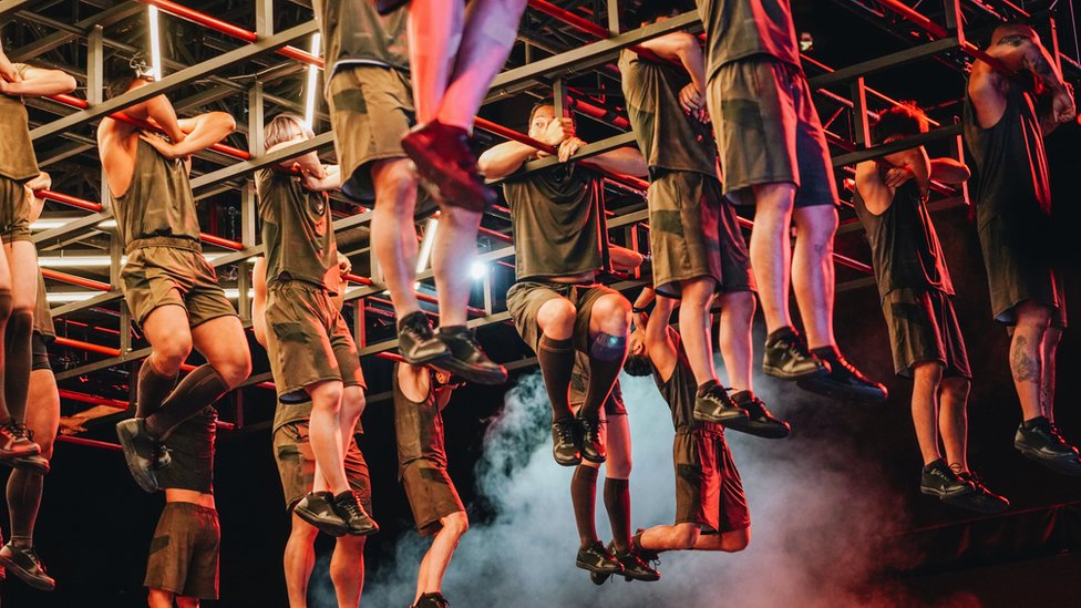 Contestants hang in the air holding on to bars for as long as possible